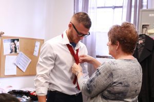 Academy of Hair Design educator helps model tie a red tie